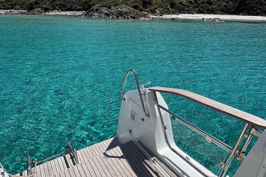 A boat on turquoise water with a wooden deck and metal railings. 4