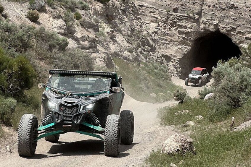 Un quad sur un chemin de terre, avec un tunnel rocheux en arrière-plan. 3