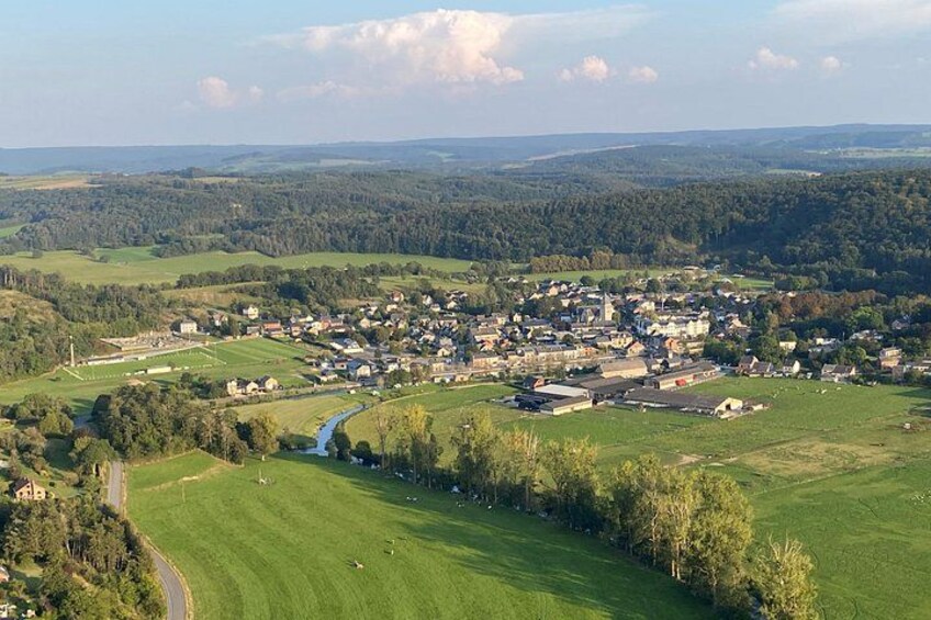 A rural town surrounded by green fields and a river. 2