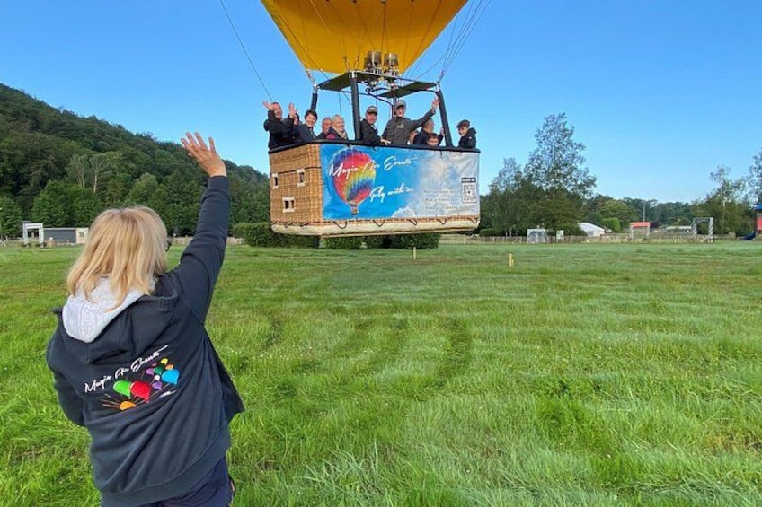 A hot air balloon with passengers, a grassy field, and a hilly landscape in the background. 3