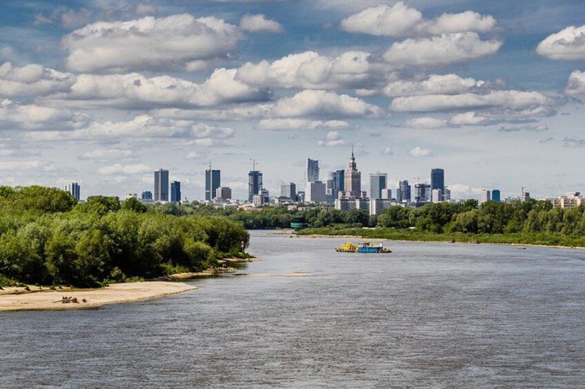Une rivière avec, en arrière-plan, la silhouette d’une ville, un bateau sur l’eau et une végétation luxuriante le long des rives. 5