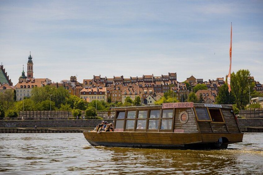 Un bateau en bois sur l’eau, avec une vue sur la ville en arrière-plan. 1