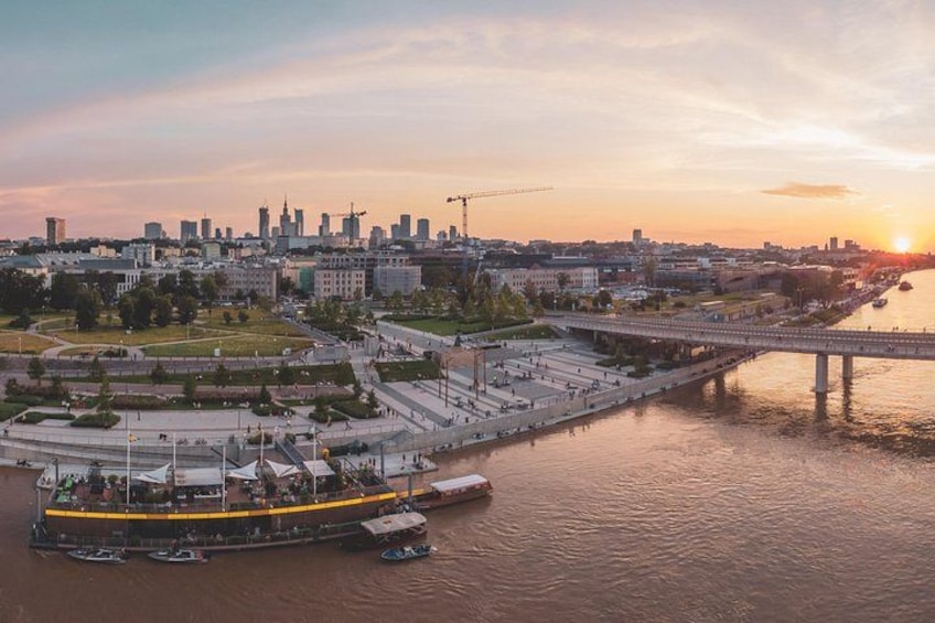 Une vue urbaine le long d’une rivière, avec un pont, une promenade en bord de mer et un coucher de soleil. 3