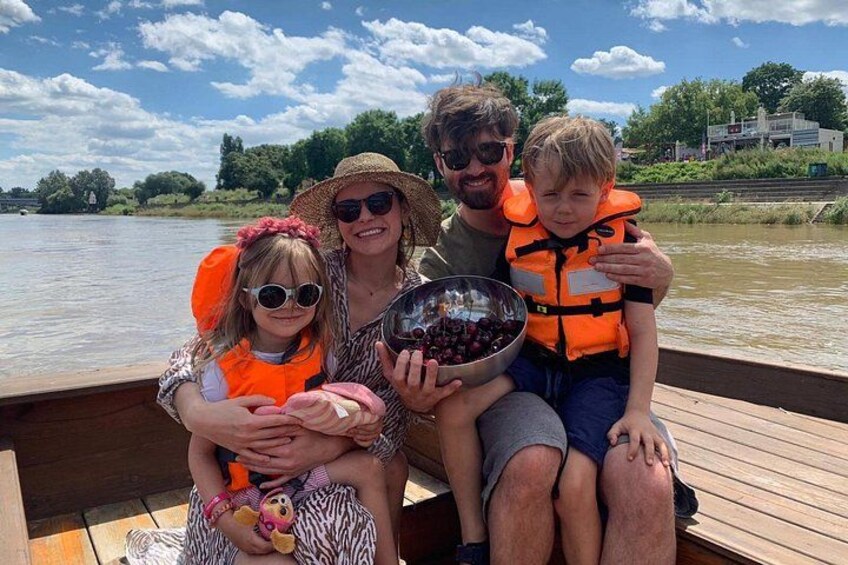 Une famille à bord d’un bateau en bois, avec une rivière et de la végétation en arrière-plan. 4