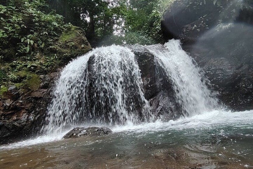 A waterfall cascading over rocks in a forested area. 1