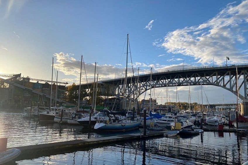 A marina with boats docked, a bridge in the background, and a clear sky. 3
