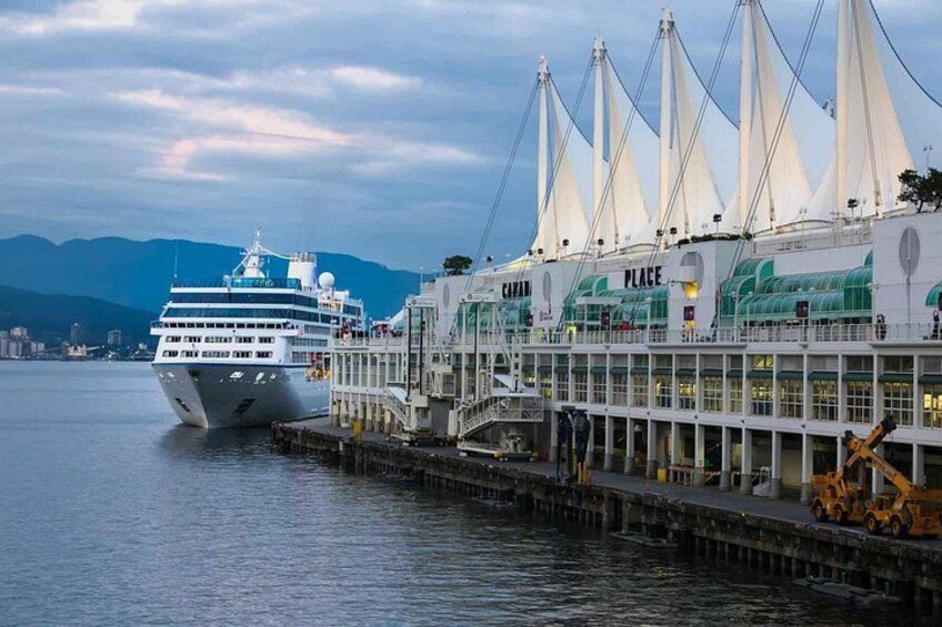 A cruise ship docked at a pier with a building labeled 'PLACE' in the background. 2