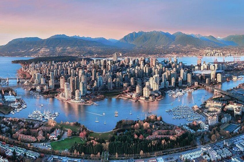 A coastal cityscape with dense urban development, a marina, and mountains in the background. 1