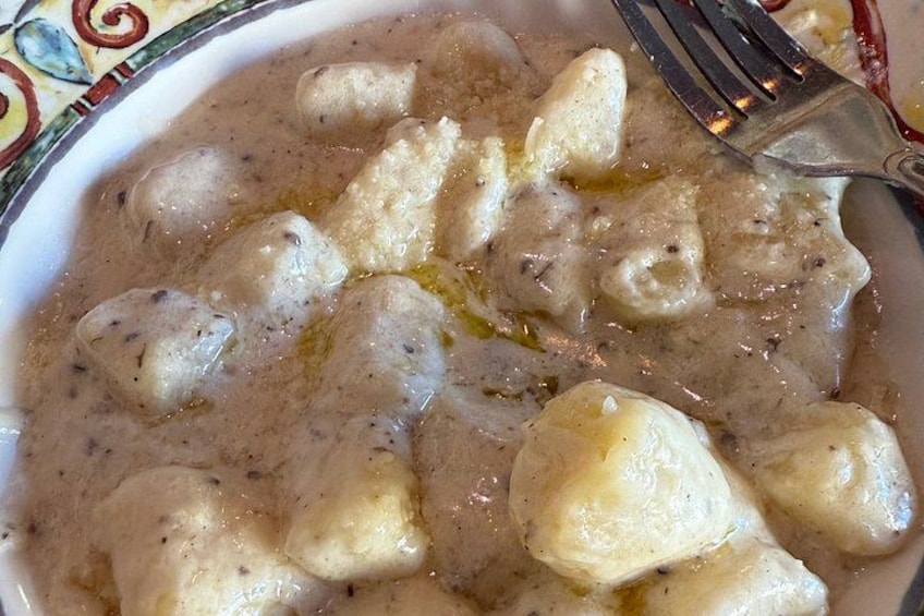 A bowl of gnocchi in a creamy sauce with a fork. 2