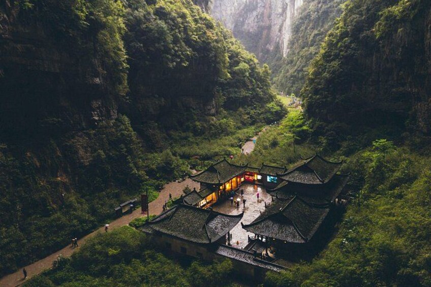 Un ensemble de bâtiments traditionnels chinois niché dans une vallée verdoyante, bordée de falaises abruptes. 4