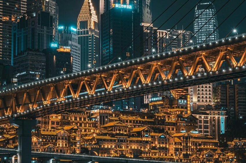 Une vue nocturne d’une ville, avec des bâtiments illuminés et un pont imposant. 3