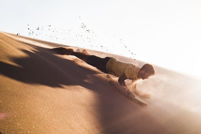 A person sliding down a sandy slope. 3