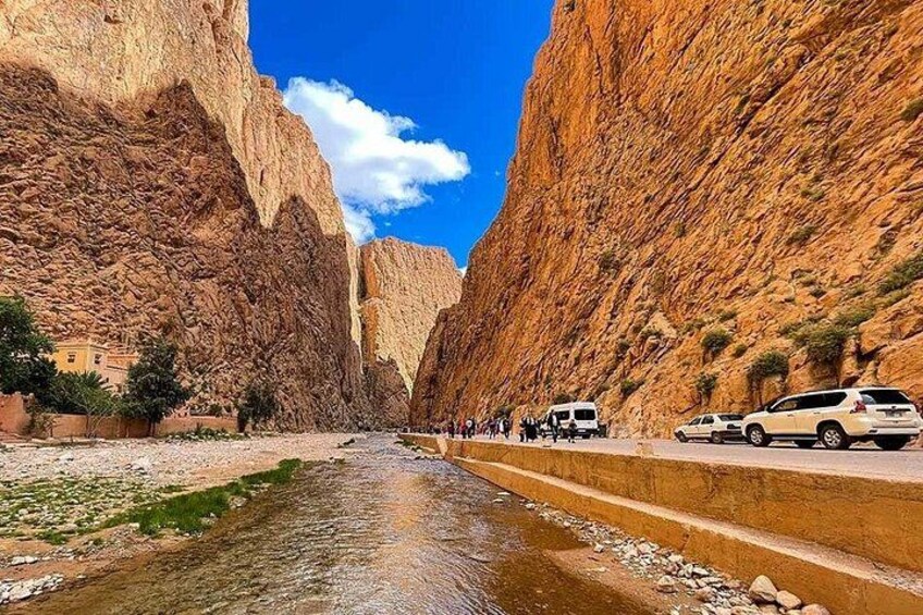 A canyon with a river, steep cliffs, and parked cars along the roadside. 2