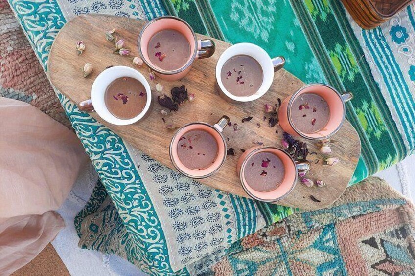 A wooden tray with four cups of tea, a patterned cloth, and a green and blue fabric. 5