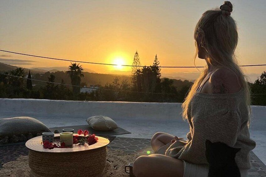A person sitting on a rooftop with a sunset in the background. 3