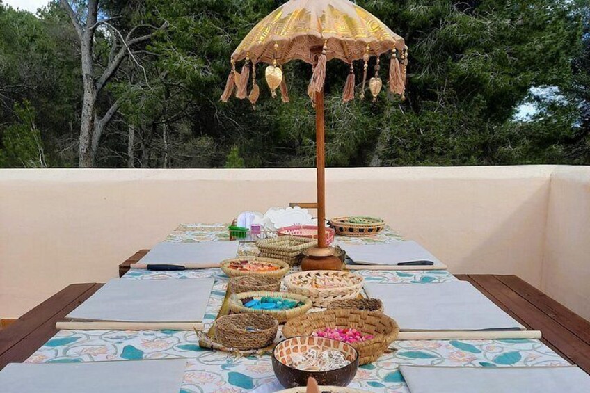 A table with baskets of food, a tablecloth, and a hanging umbrella on an outdoor patio. 4