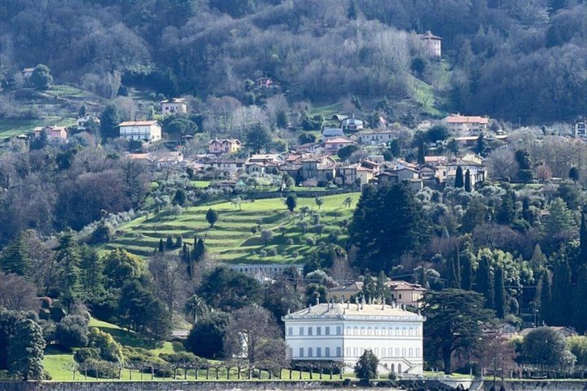 A village with terraced fields, a prominent white building, and scattered houses on a hillside. 2