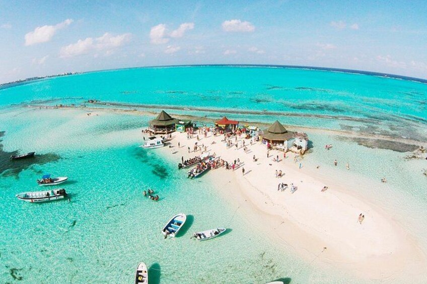 A tropical beach with clear turquoise waters, a sandy shore, and several small boats. 2