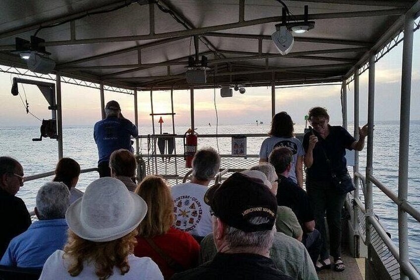 A group of people on a boat, some standing and some seated, looking out at the sea. 2