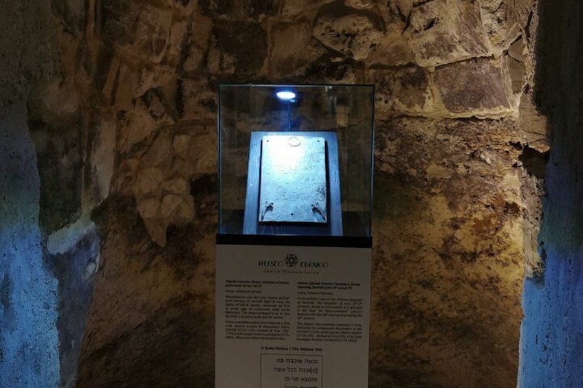 Een stenen muur met een glazen vitrine waarin een artefact ligt. 3
