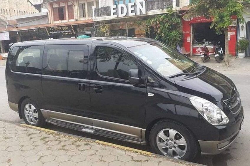A black minivan parked on a cobblestone street with buildings in the background. 4