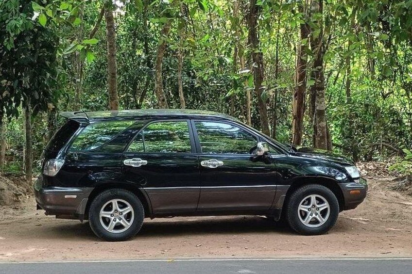 A black car parked on a dirt road in a forested area. 3