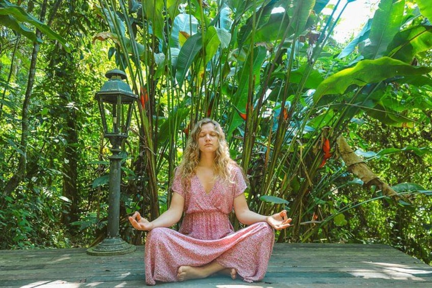 A person sitting cross-legged in a garden with lush greenery and a street lamp. 1