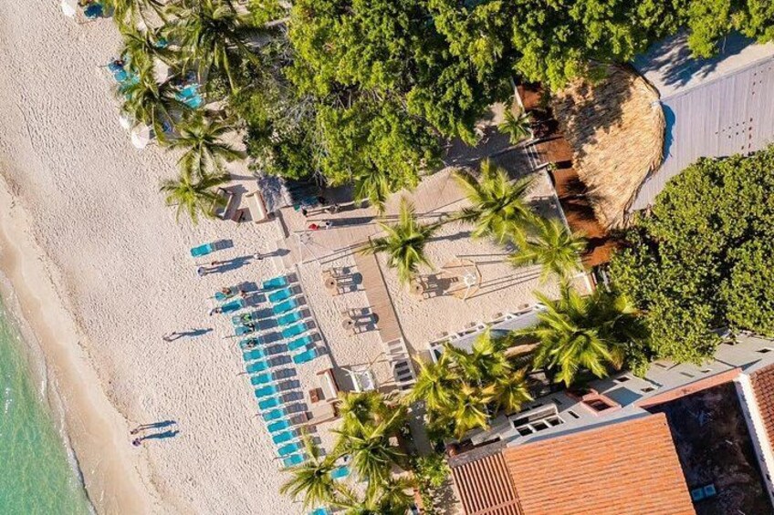 Vista aerea di una spiaggia con lettini, palme e un edificio. 2