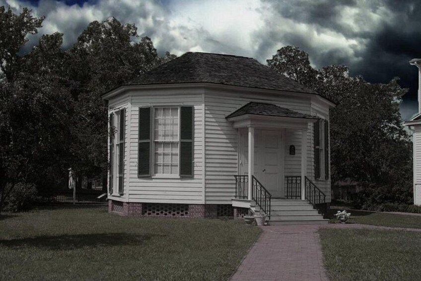 A white house with a porch and steps, surrounded by grass and trees. 2