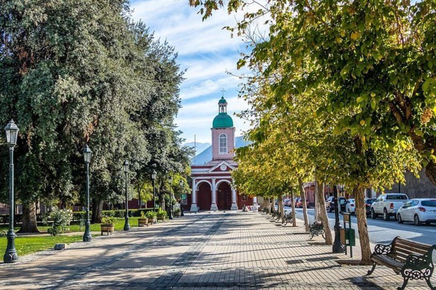 A paved pathway lined with trees and benches, leading to a building with a green dome. 5