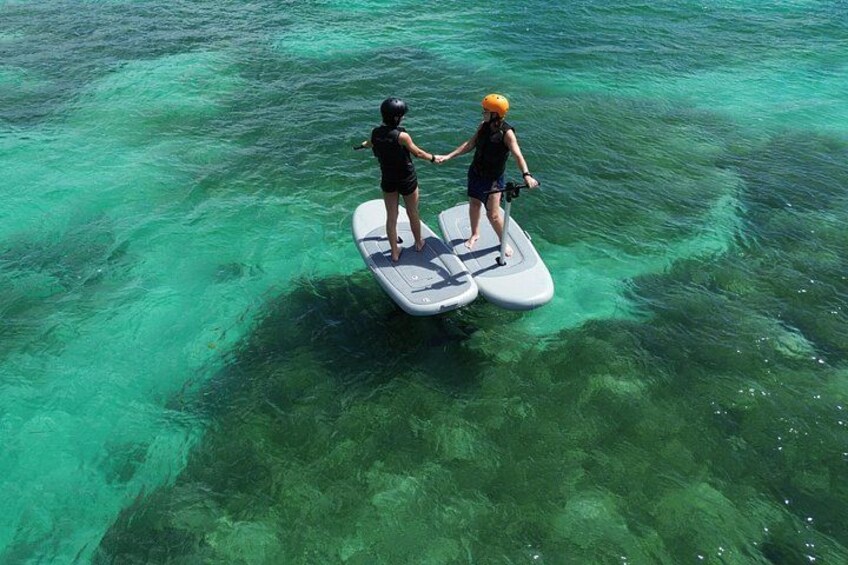 Zwei Personen stehen auf einer schwimmenden Plattform in klarem türkisblauem Wasser. 3