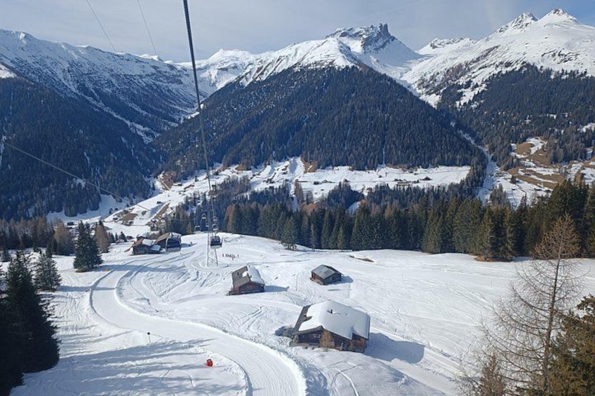 A snow-covered mountain landscape with ski lifts, buildings, and a winding road. 2