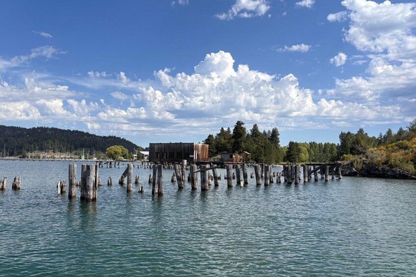 A wooden pier extending into a calm lake, surrounded by trees and a clear sky. 2