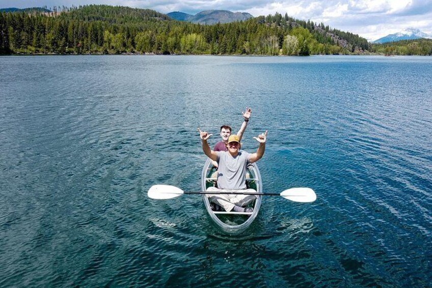 A person in a canoe on a calm lake surrounded by forested hills. 3