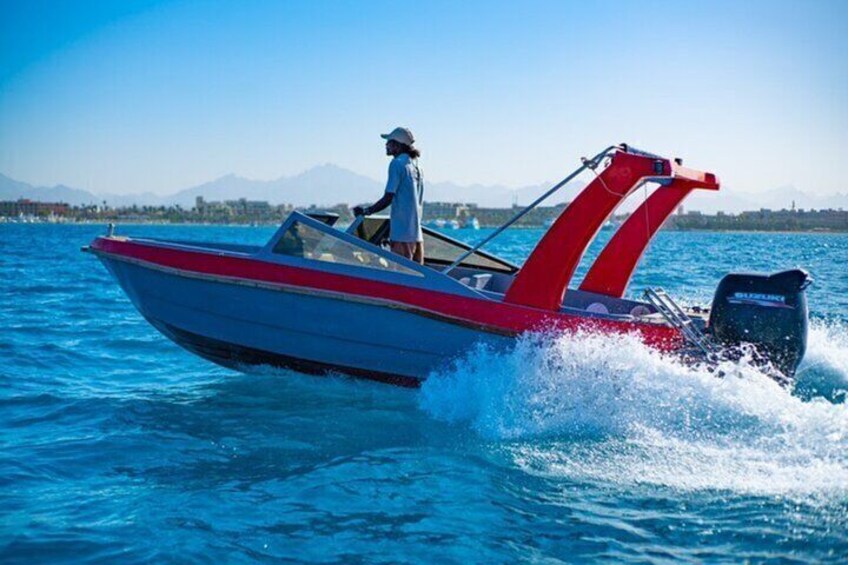 Un motoscafo con schema di colori rosso e bianco che naviga in acqua, con una persona al timone. 1