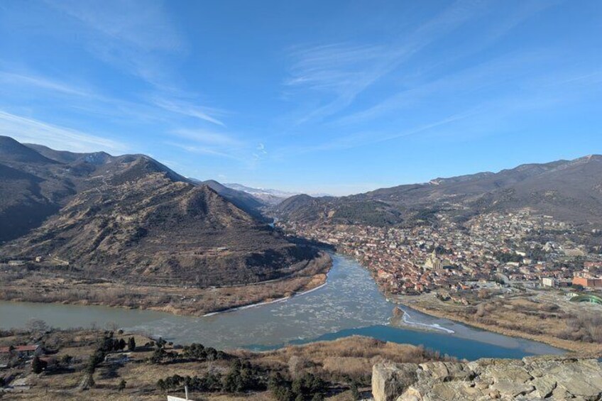 Une rivière serpente à travers une vallée, avec des montagnes en arrière-plan et une ville sur la droite. 4