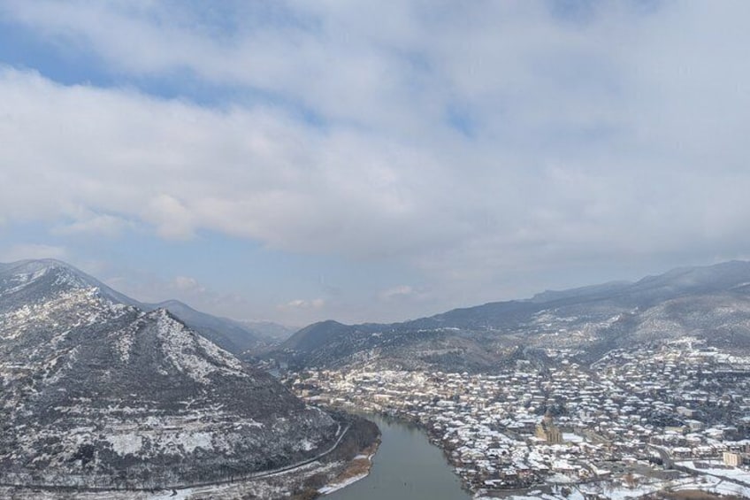 Un paysage montagneux enneigé, avec une rivière et une ville. 3