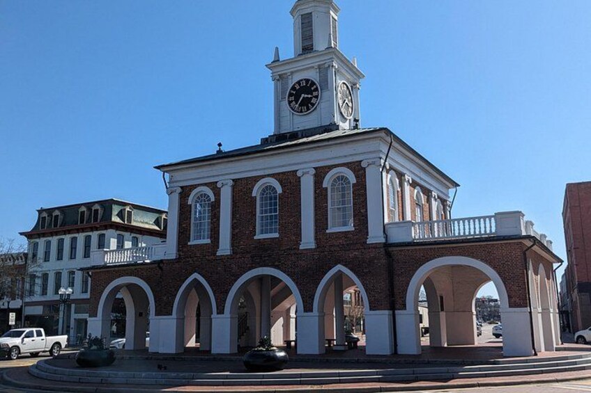 A historic building with a clock tower, arched windows, and a balcony. 1