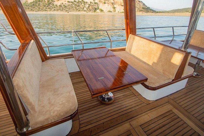 Cubierta de barco con suelo de madera, asientos acolchados y una mesa. 3