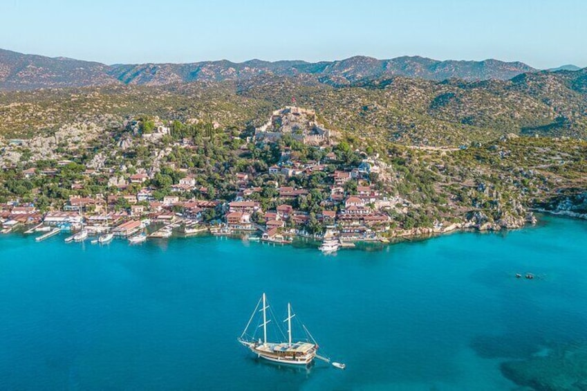 Un pueblo costero con un puerto, barcos y montañas al fondo. 1
