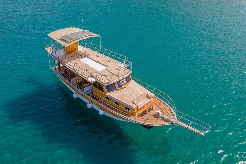 Un barco de madera con cabina y cubierta, flotando sobre aguas turquesas cristalinas. 2