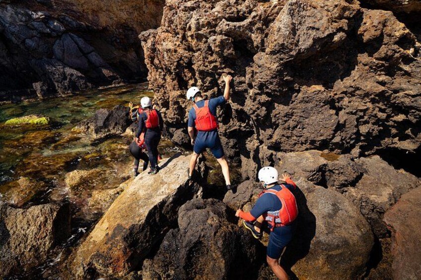 A group of people climbing rocky terrain with a body of water in the background. 3