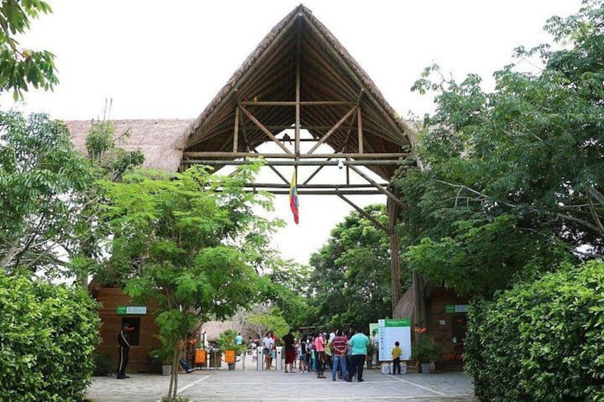 A large wooden structure with a triangular roof, surrounded by trees and a paved walkway. 3