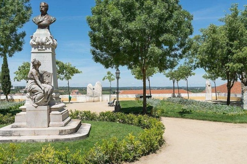 A statue in a park with trees and a clear sky. 4