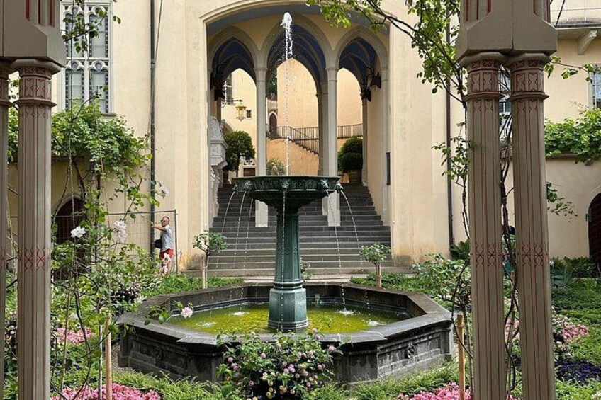 A fountain surrounded by flowers and greenery, with a building in the background. 4