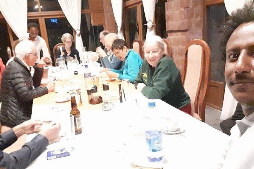 A group of people seated around a long table with food and drinks. 3
