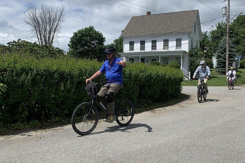 A cyclist on a road with a house and greenery in the background. 2