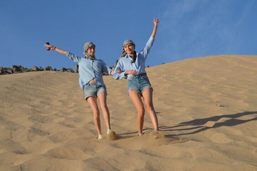 Two people balancing on a sand dune with a clear sky. 2