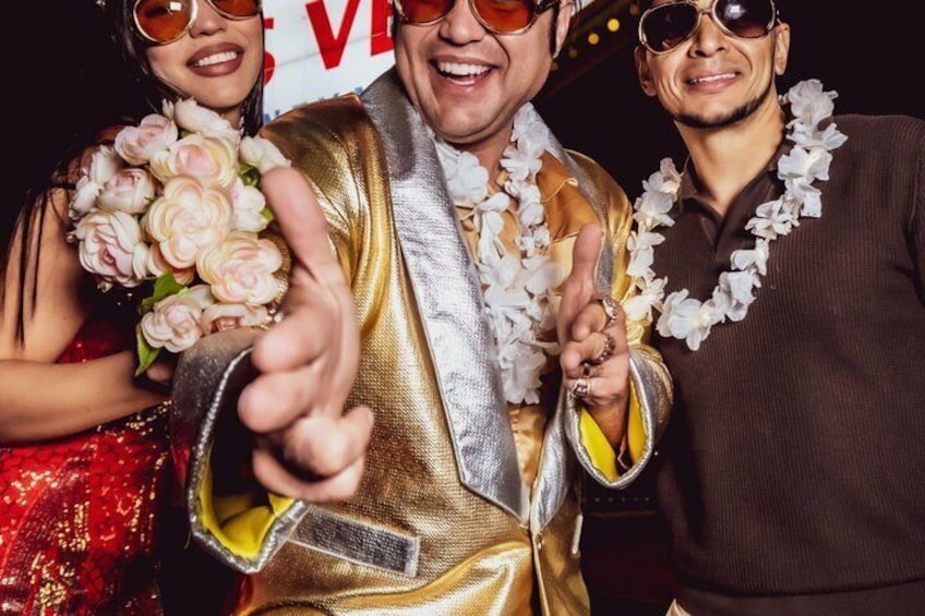 Une personne portant une veste dorée, une chemise blanche et un collier de fleurs. 1