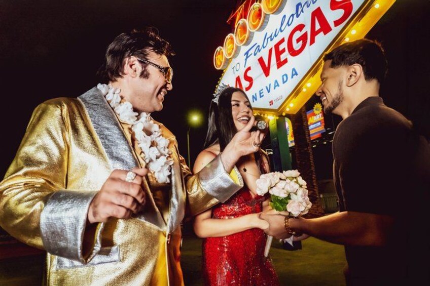 A neon sign with 'Las Vegas' written on it, a person in a gold jacket, and another in a red dress holding a bouquet. 3